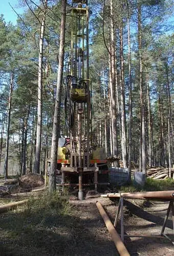 An environmental driller against a backdrop of trees.