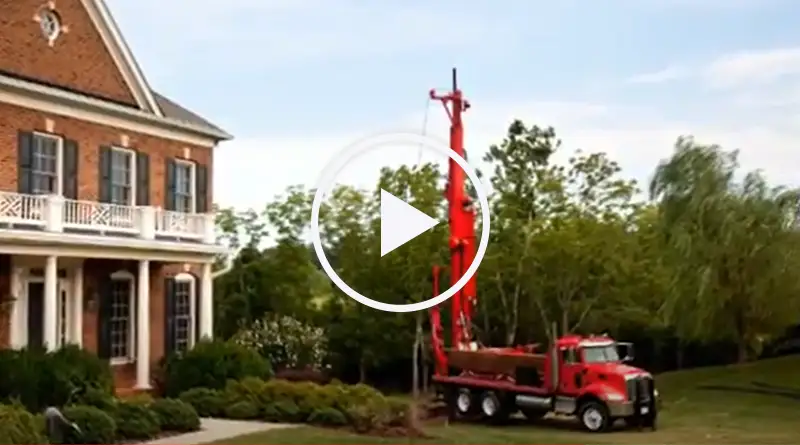 A red Rodgers Well Drilling Truck in front of a large brick building.